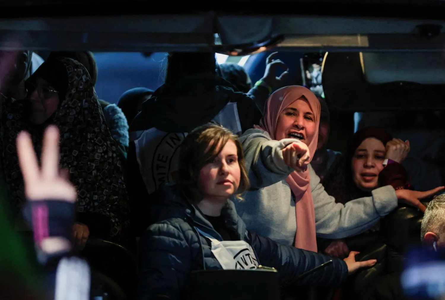 أسير فلسطيني محرَّر يلوّح بيده داخل حافلة وصلت بعد إطلاق سراحه في إطار صفقة تبادل أسرى واتفاق وقف النار بين «حماس» وإسرائيل (رويترز)