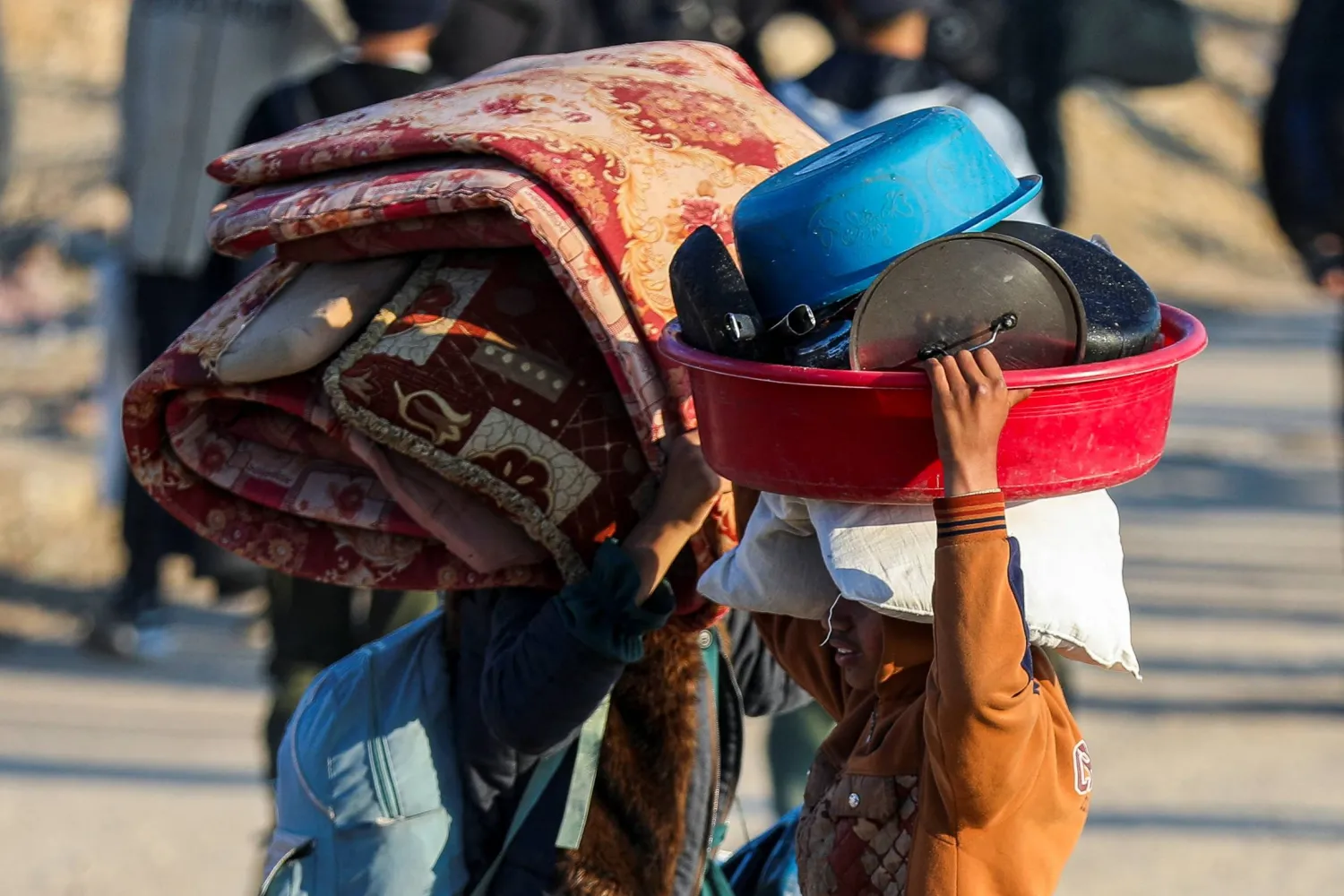 عائلة تحمل أغطية وأواني وهم يشقون طريقهم سيراً على الأقدام نحو شمال قطاع غزة (رويترز)