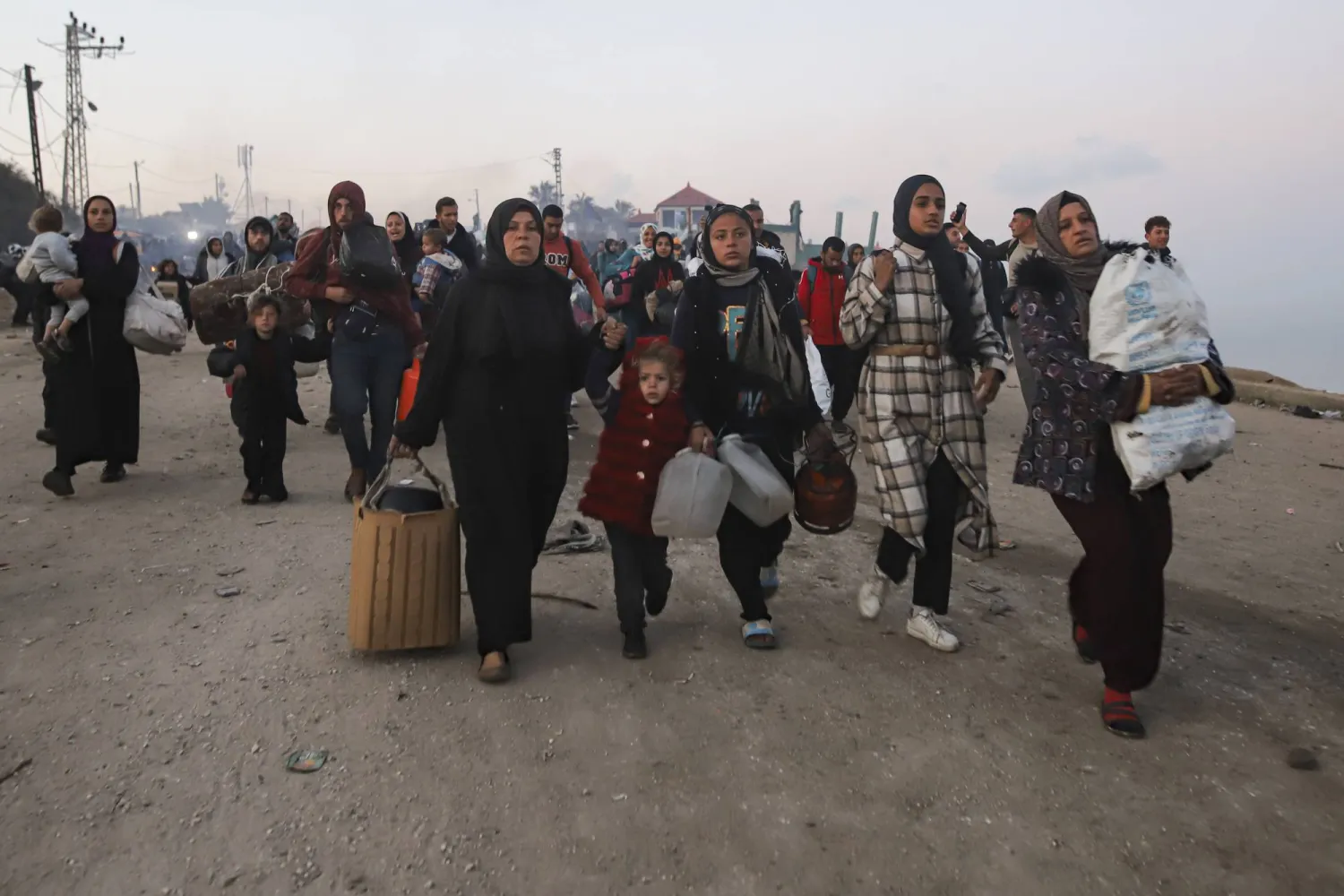 عائلة تحمل ما تبقّى لها من أمتعة بعد مرات عدة من النزوح خلال أيام الحرب بقطاع غزة (أ.ب)