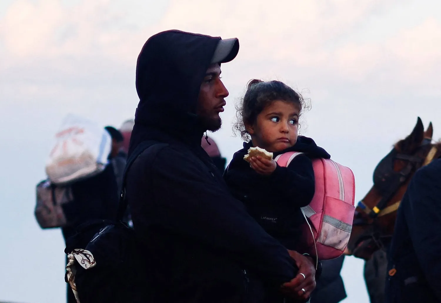 فلسطيني يحمل طفلته الصغيرة في رحلة العودة إلى منزلهم بشمال غزة (رويترز)