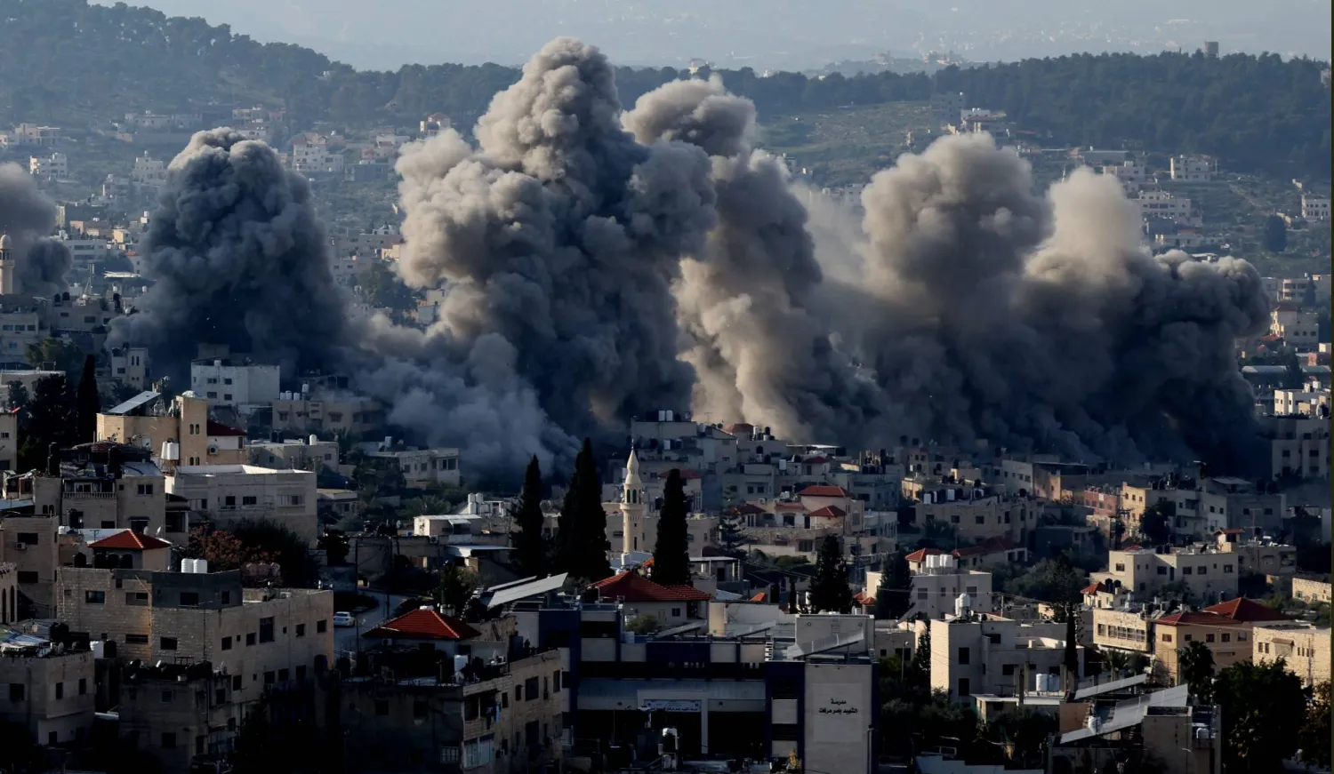 دخان يتصاعد نتيجة نسف الجيش الإسرائيلي كثيراً من المباني في مخيم جنين بالضفة الغربية (إ.ب.أ)