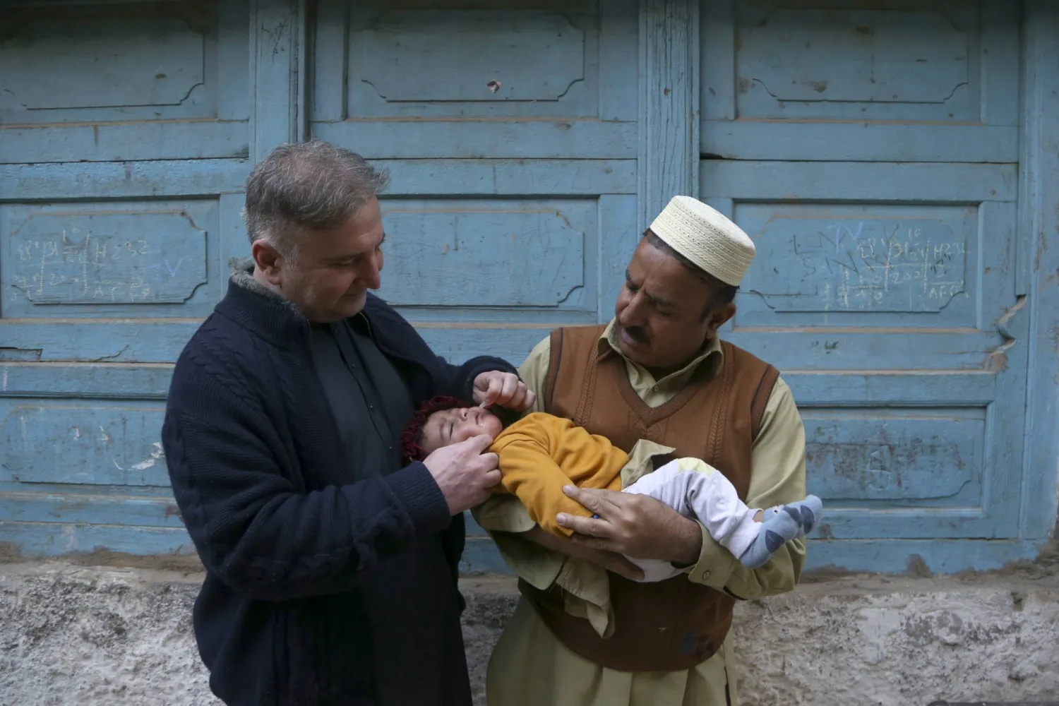 عامل صحي (على اليسار) يعطي طفلاً لقاح شلل الأطفال في أحد أحياء بيشاور بباكستان الاثنين 3 فبراير 2025 (أ.ب)