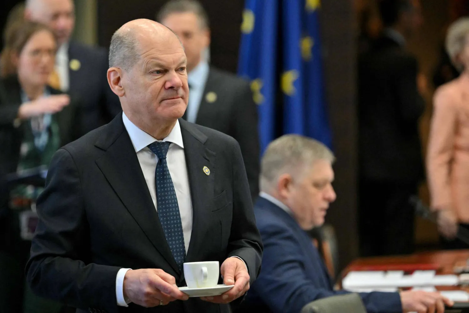 شولتس يمشي بفنجانه قبل بدء اجتماع المائدة المستديرة في القمة غير الرسمية لزعماء الاتحاد الأوروبي ببروكسل (أ.ف.ب)