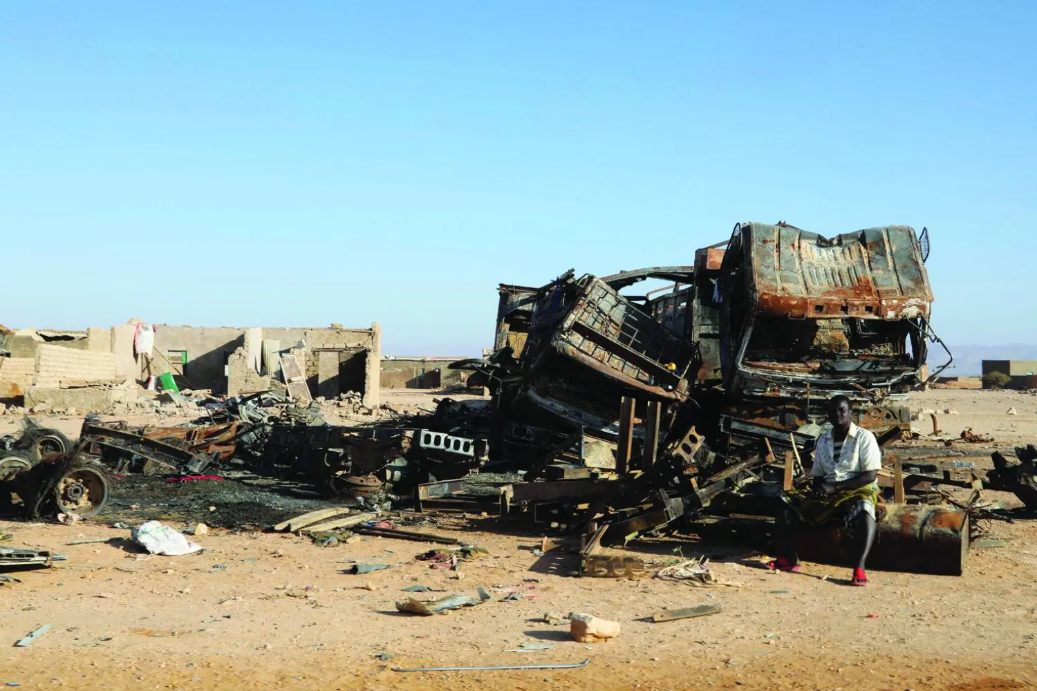صومالي يجلس بجوار حطام مركبات عسكرية محترقة استخدمها «داعش» بمدينة بوصاصو الصومالية يناير 2025 (رويترز)