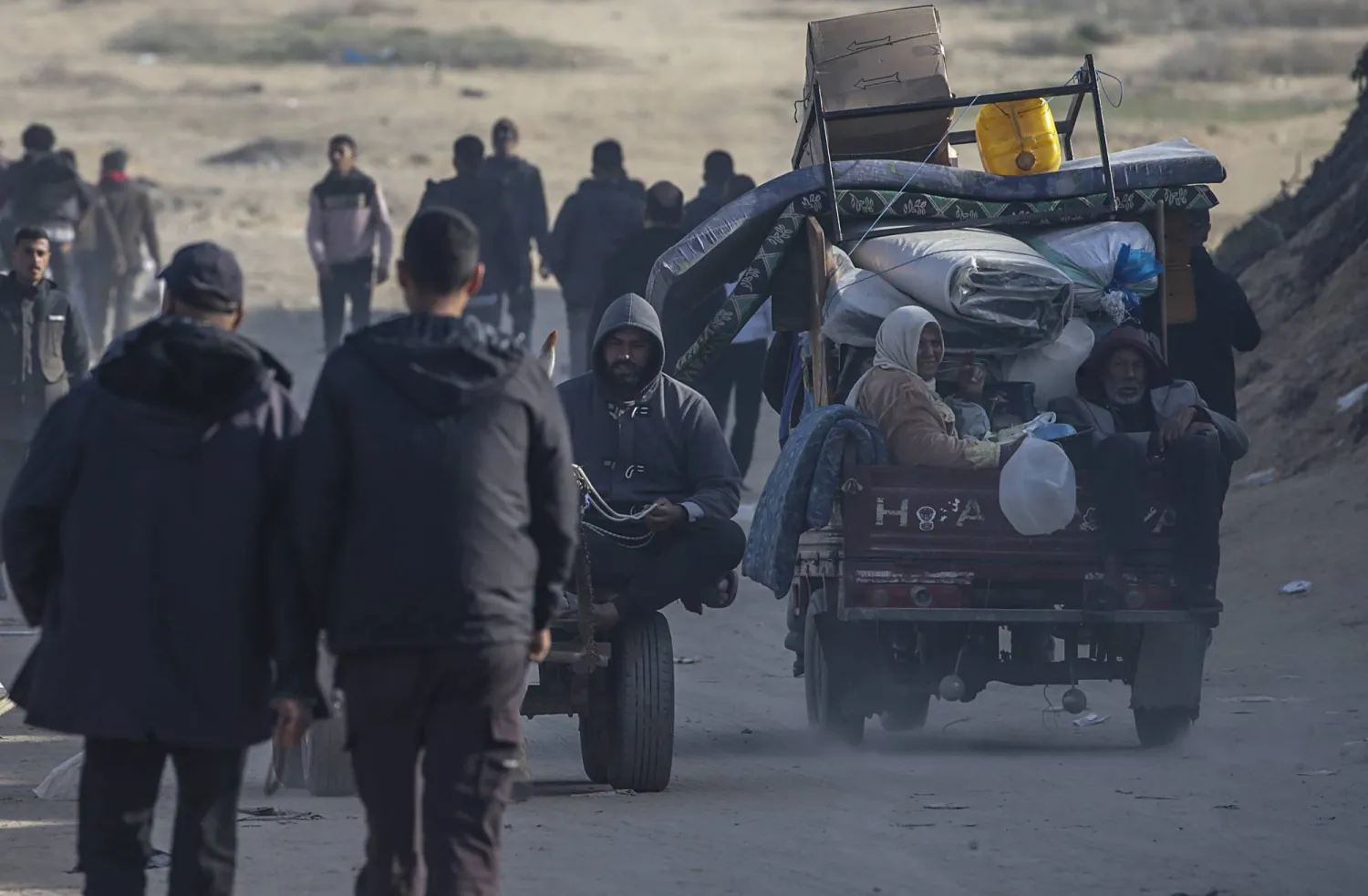 فلسطينيون يشقون طريقهم بين أنقاض المباني المدمرة وسط وقف إطلاق النار بين إسرائيل و«حماس» على طريق الرشيد بمدينة غزة (إ.ب.أ)