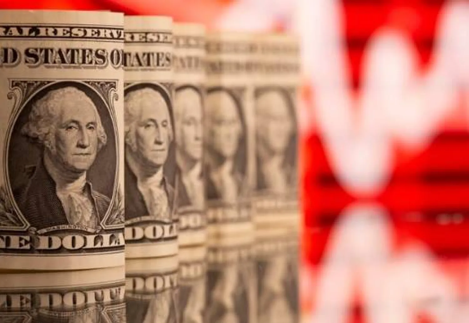 أوراق الدولار الأميركي مقابل مخطط للأسهم (رويترز)