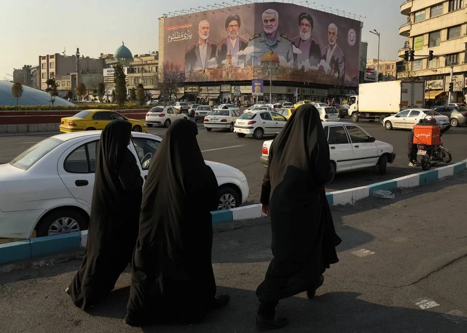 People walk on Enqelab-e-Eslami square near a huge banner showing the late commander of the Iran's Revolutionary Guard expeditionary Quds Force, Gen. Qassem Soleimani, center, who was killed in a US drone attack in 2020, and Hezbollah and Hamas officials killed by Israel, in Tehran, Iran, Tuesday, Jan. 21, 2025. (AP) 