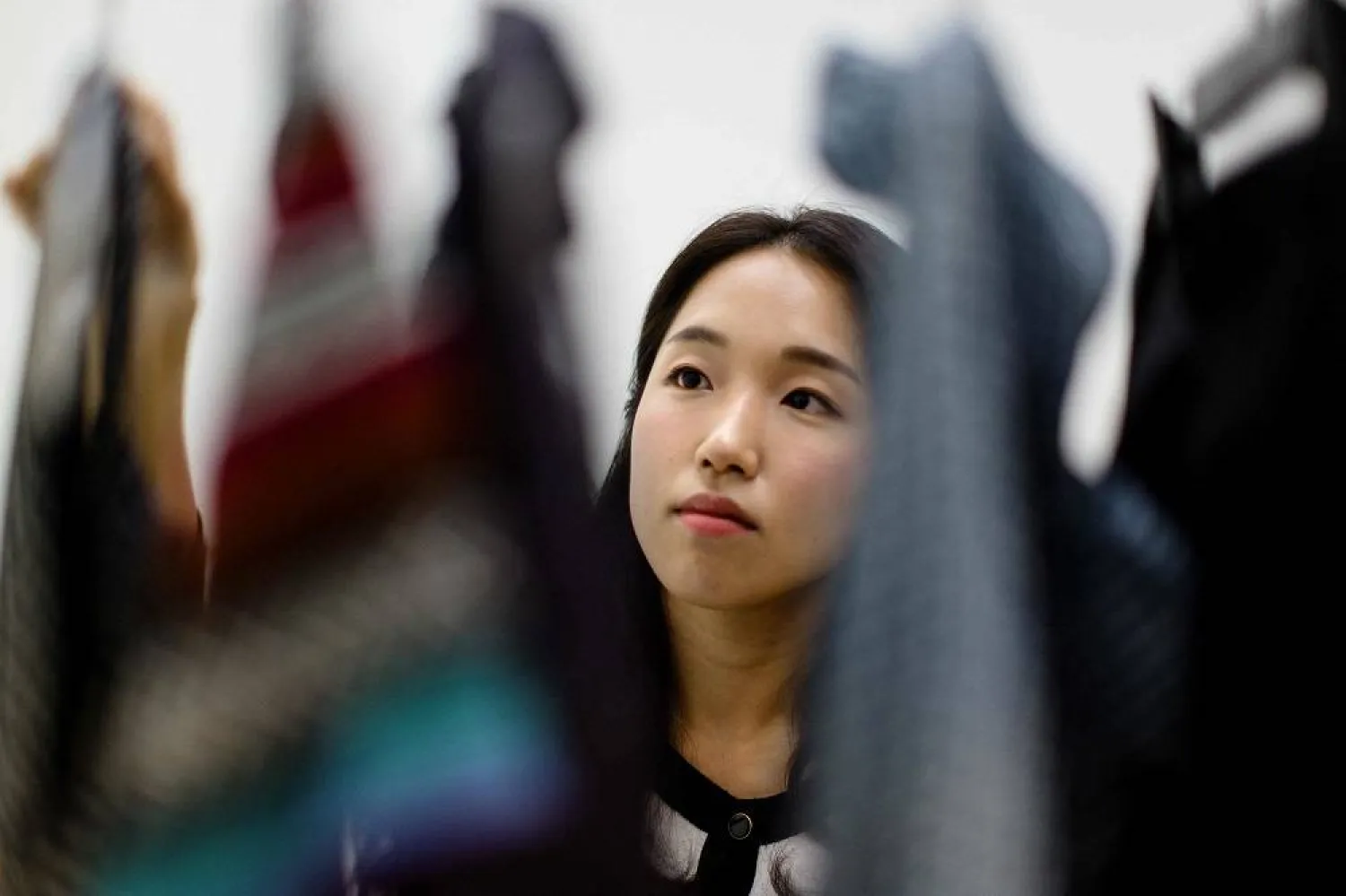 In this photograph taken on July 23, 2024, South Korean climate activist Lee So-yeon, who has not bought any new clothes for the past six years and now has a wardrobe consisting of used items that she received from friends and family, looks at a selection of her clothes, during an interview with AFP in Seoul. (AFP) 
