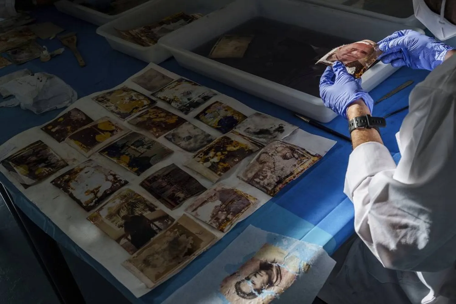 A volunteer stabilizes family photos from photo albums recovered during the devastating flash floods last year in Valencia, Spain, as part of a restoration process conducted by students and professors from the Conservation and Restoration program at a field laboratory at the Universitat Politecnica de Valencia, eastern Spain, Thursday, Jan. 16, 2025. (AP) 