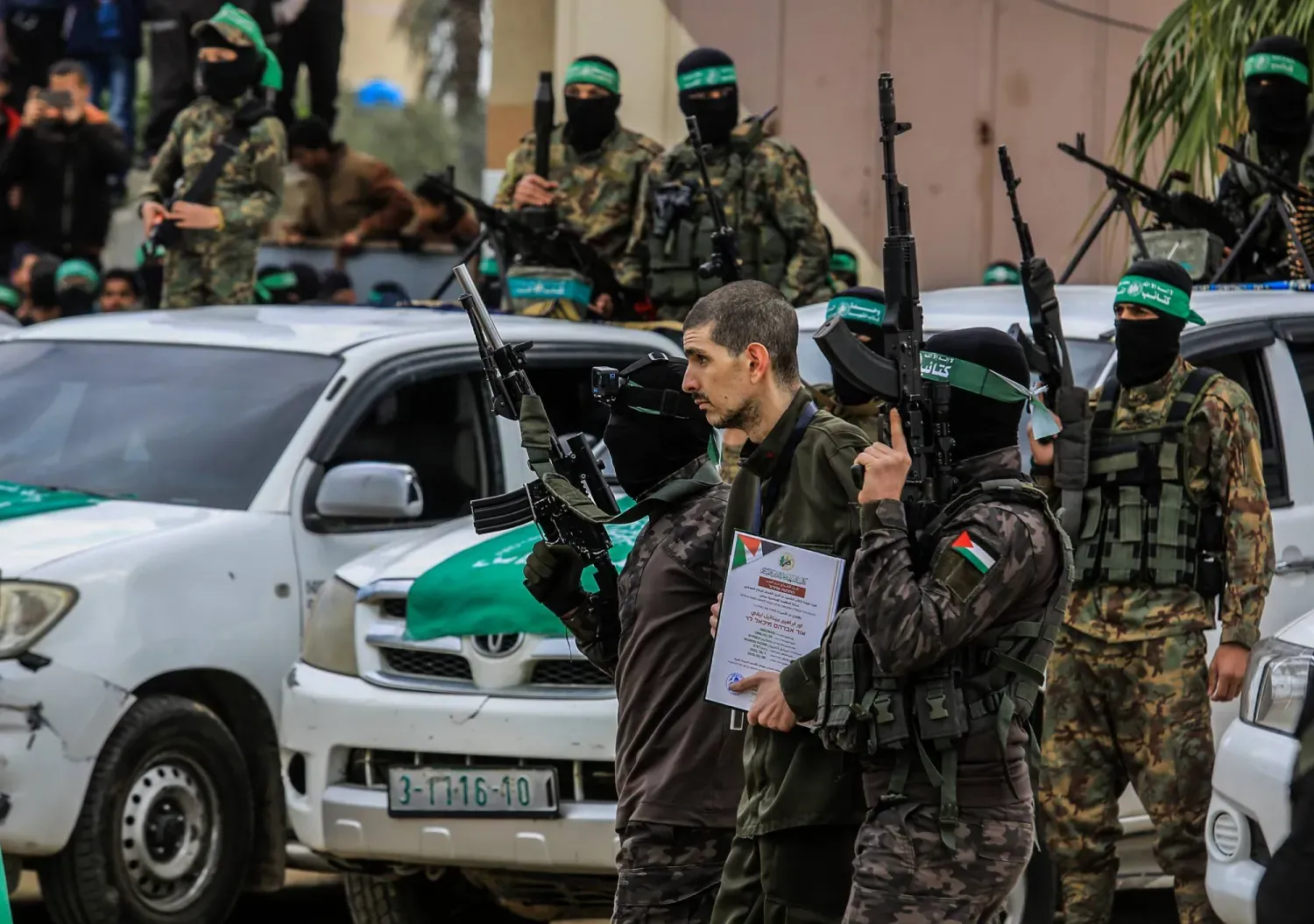 Hamas'ın askeri kanadı İzzeddin El Kassam Tugayları'ndan bir savaşçı, İsrailli rehine Or Levy'yi Uluslararası Kızılhaç Komitesi temsilcilerine teslim ederken (DPA)