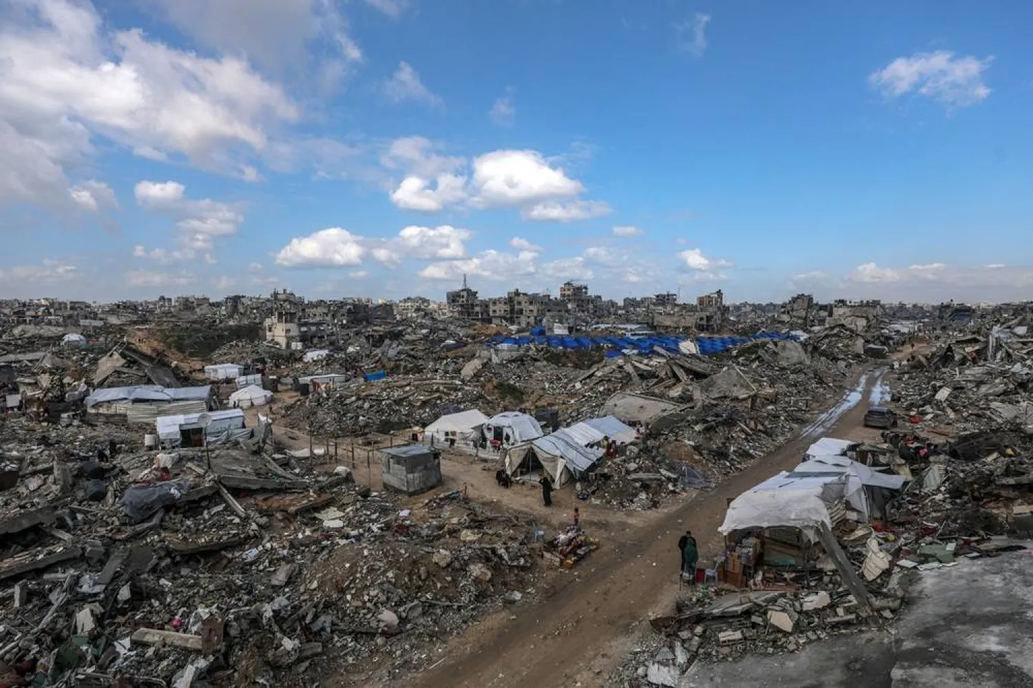 Palestinians walk past shelters of families who returned to northern Gaza, set up among the rubble of destroyed buildings amid a ceasefire between Israel and Hamas, in Jabalya, northern Gaza Strip, 13 February 2025. (EPA)