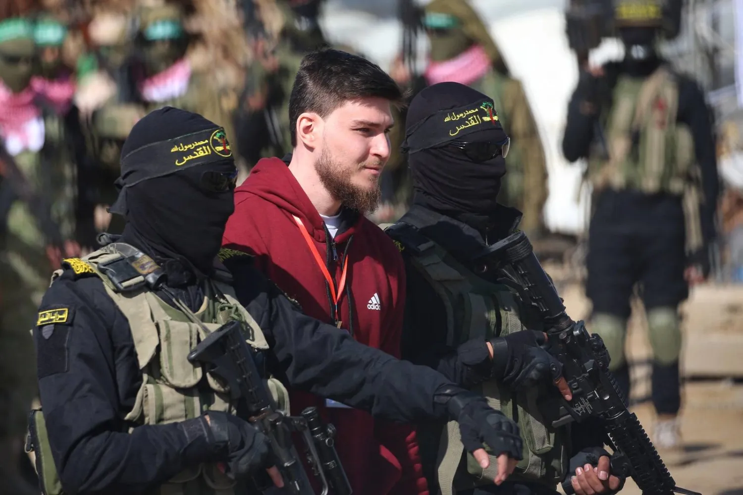 مقاتلون من «حركة الجهاد الإسلامي» يرافقون رهينة قبل تسليمه إلى فريق الصليب الأحمر بخان يونس جنوب غزة (أ.ف.ب)