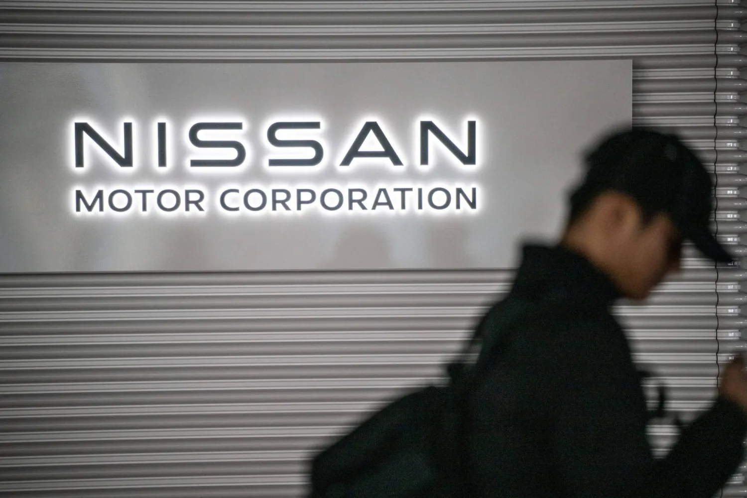 (FILES) This file photo taken on February 10, 2025 shows a man walking past the Nissan logo in the showroom at Nissan's global headquarters in Yokohama, Kanagawa prefecture. (Photo by Philip FONG / AFP)