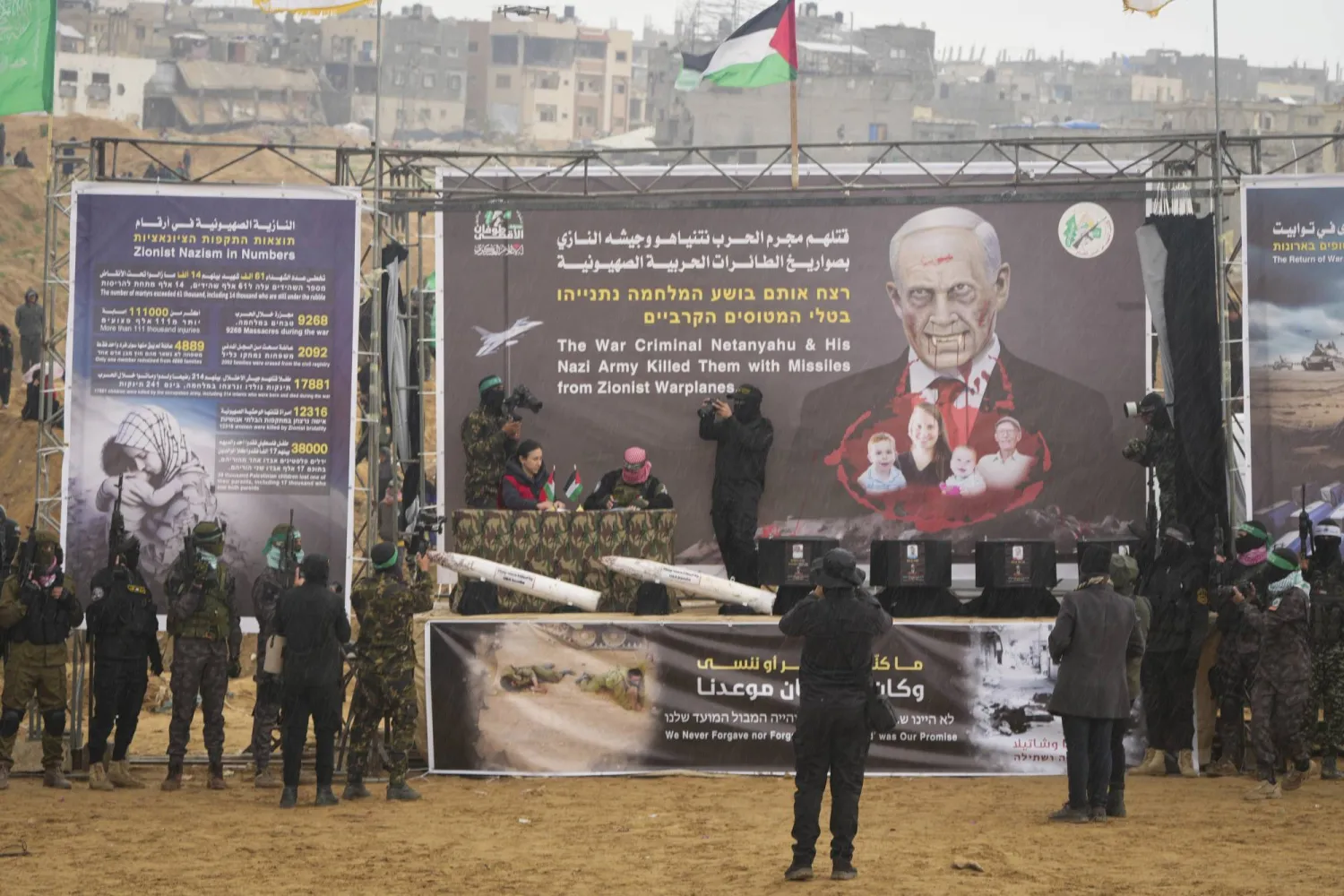 A Red Cross representative signs a document as coffins containing the bodies of four people are displayed on a stage before being handed over by Hamas and Islamic Jihad in Khan Younis, southern Gaza Strip, Thursday, Feb. 20, 2025. (AP Photo/Abdel Kareem Hana)