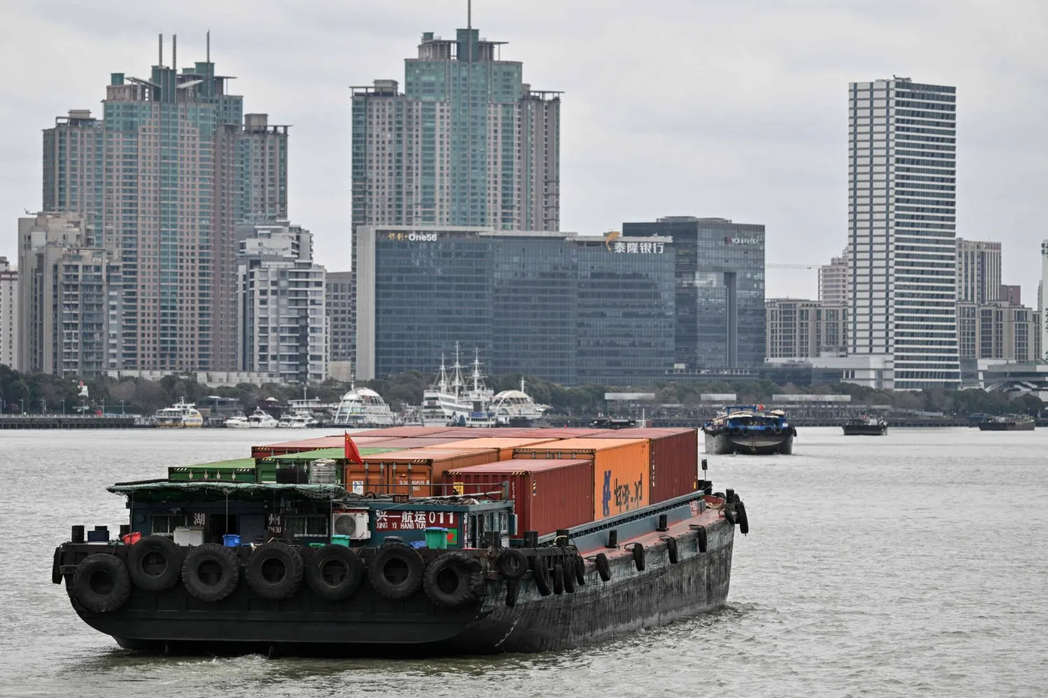 مراكب تبحر في نهر هوانغبو مقابل الحي المالي بمدينة شنغهاي الصينية (أ.ف.ب)