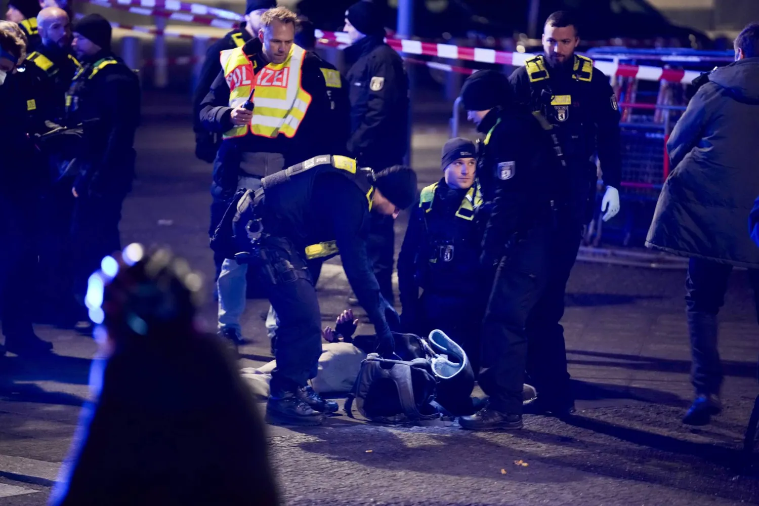 عناصر من الشرطة الألمانية يعتقلون رجلاً بموقع الهجوم في برلين (أ.ب)