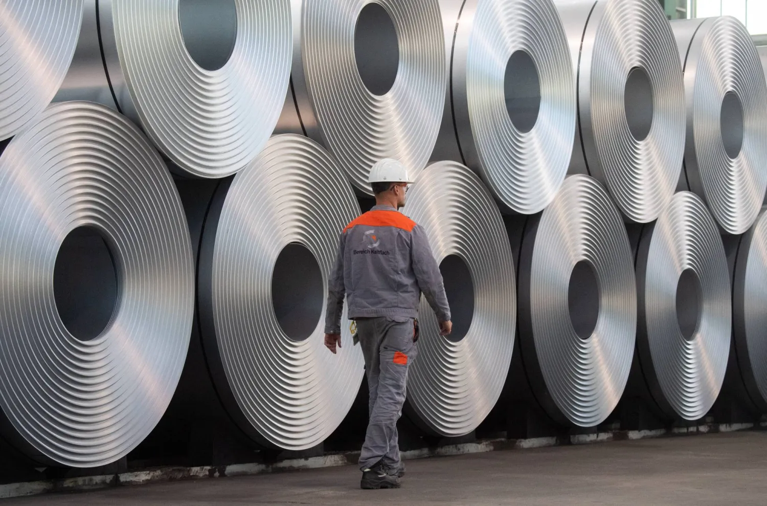 FILED - 12 July 2020, Lower Saxony, Salzgitter: An employee walks along coiled steel at Salzgitter AG. Photo: Julian Stratenschulte/dpa