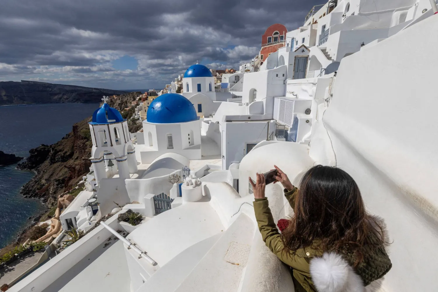 A tourist takes a photo at the village of Oia, as the seismic activity continues, on the island of Santorini, Greece, February 22, 2025. REUTERS/Nicolas Economou