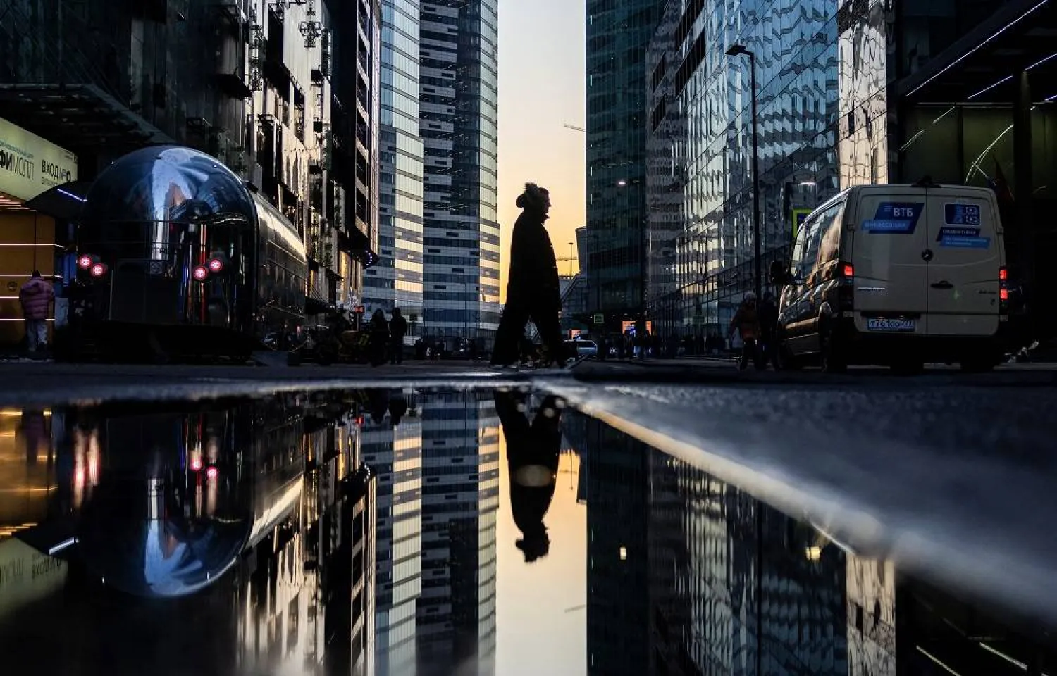 A pedestrian walks past a puddle near buildings of the Moscow City international business center during sunset in Moscow, Russia, February 23, 2025. (Reuters)