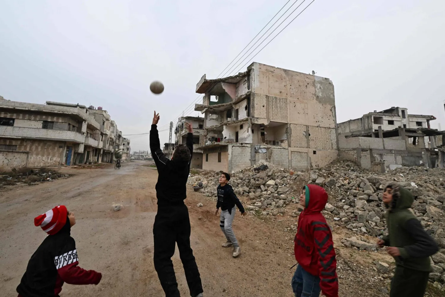 Syrian children play in the heavily damaged Baba Amr neighborhood following the return of their families to the central Syrian city of Homs on February 10, 2025. (Photo by LOUAI BESHARA / AFP)