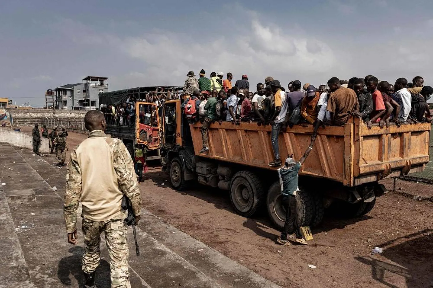 A member of the M23 movement stands guard as people board a truck during an enrollment of civilians, police officers, and former members of the Armed Forces of the Democratic Republic of Congo (FARDC) who allegedly decided to join the M23 movement voluntarily in Goma on February 23, 2025. (AFP)