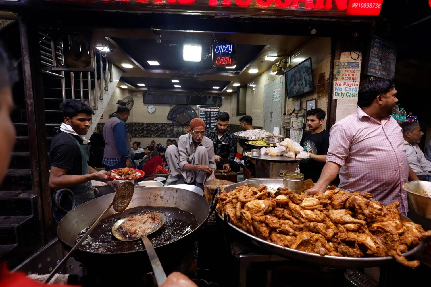 بائعو الأطعمة يعدُّون الوجبات في أحد المطاعم بالهند (رويترز)