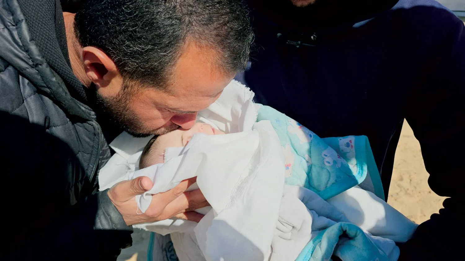  الرضيعة الفلسطينية شام الشنباري التي توفيت أمس من جراء البرد القارس في غزة يقبلها أحد أقاربها قبل دفنها (الشرق الأوسط)