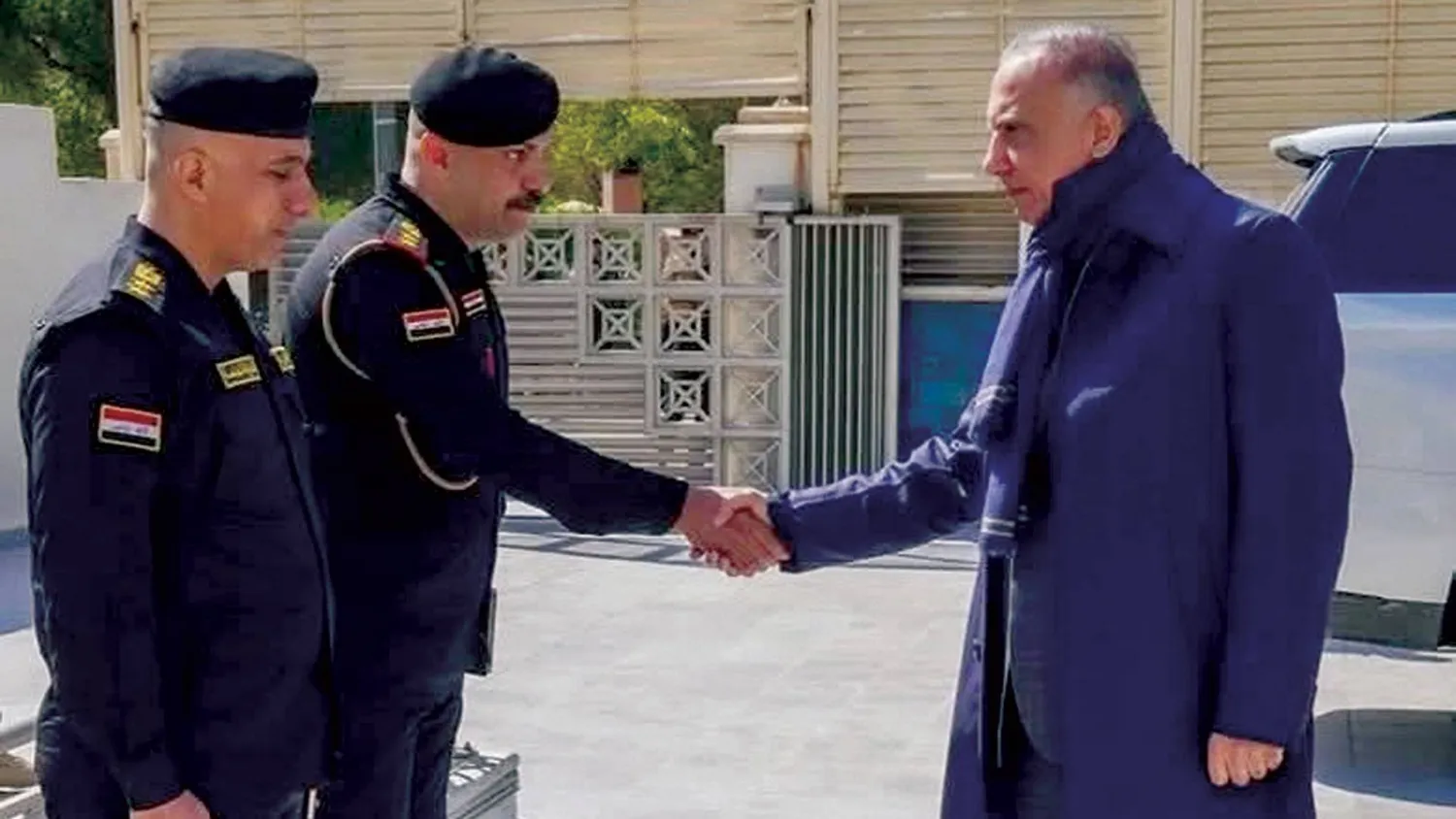 الكاظمي مصافحاً ضابط شرطة قرب منزله في المنطقة الخضراء (إكس)