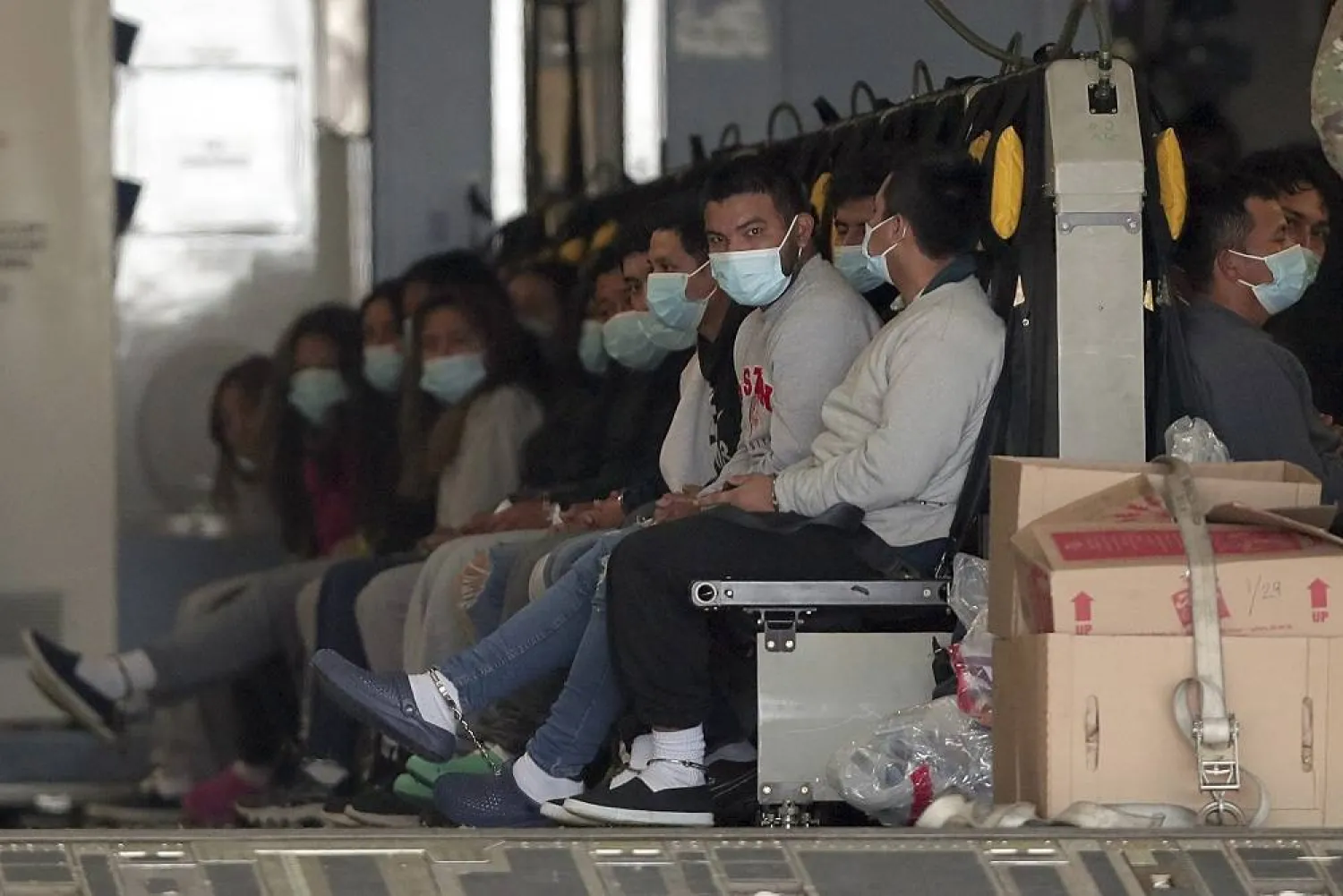 Migrants wearing face masks and shackles on their hands and feet sit on a military aircraft at Fort Bliss in El Paso, Tx., Jan. 30, 2025, awaiting their deportation to Guatemala. (AP) 