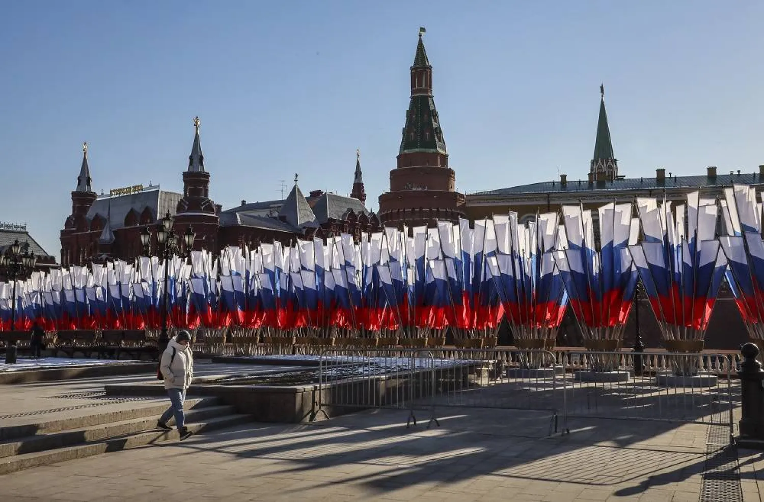 A woman walks next to Russian flags placed in front of the Kremlin on a clear sunny day in Moscow, Russia, 25 February 2025. (EPA)