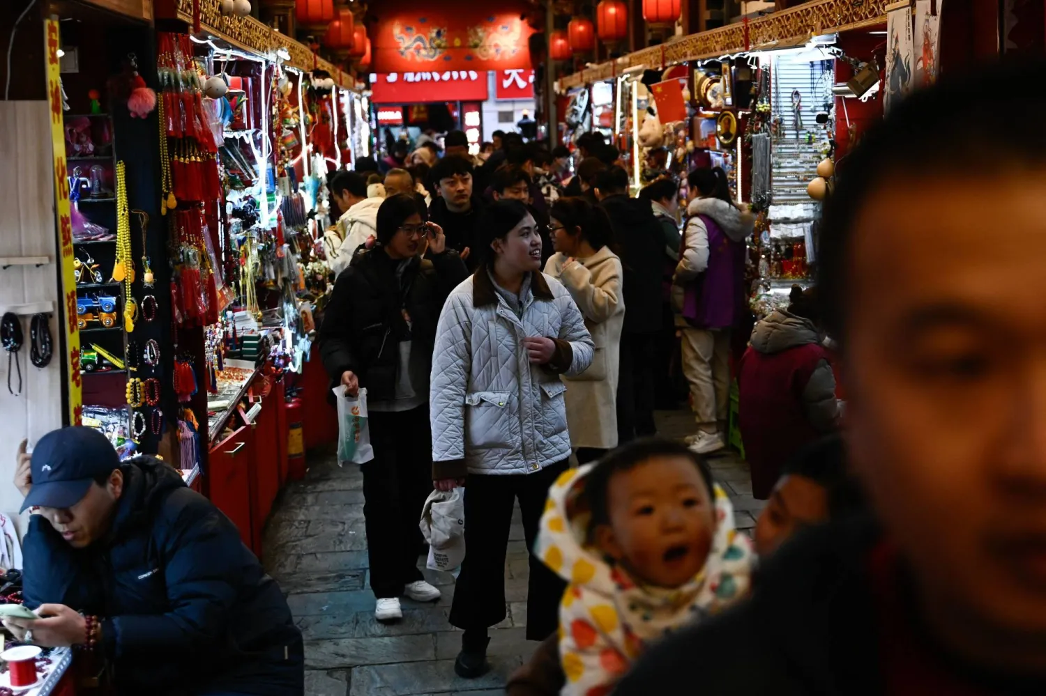 مشاة في إحدى أسواق الهدايا الشعبية وسط بكين (أ.ف.ب)
