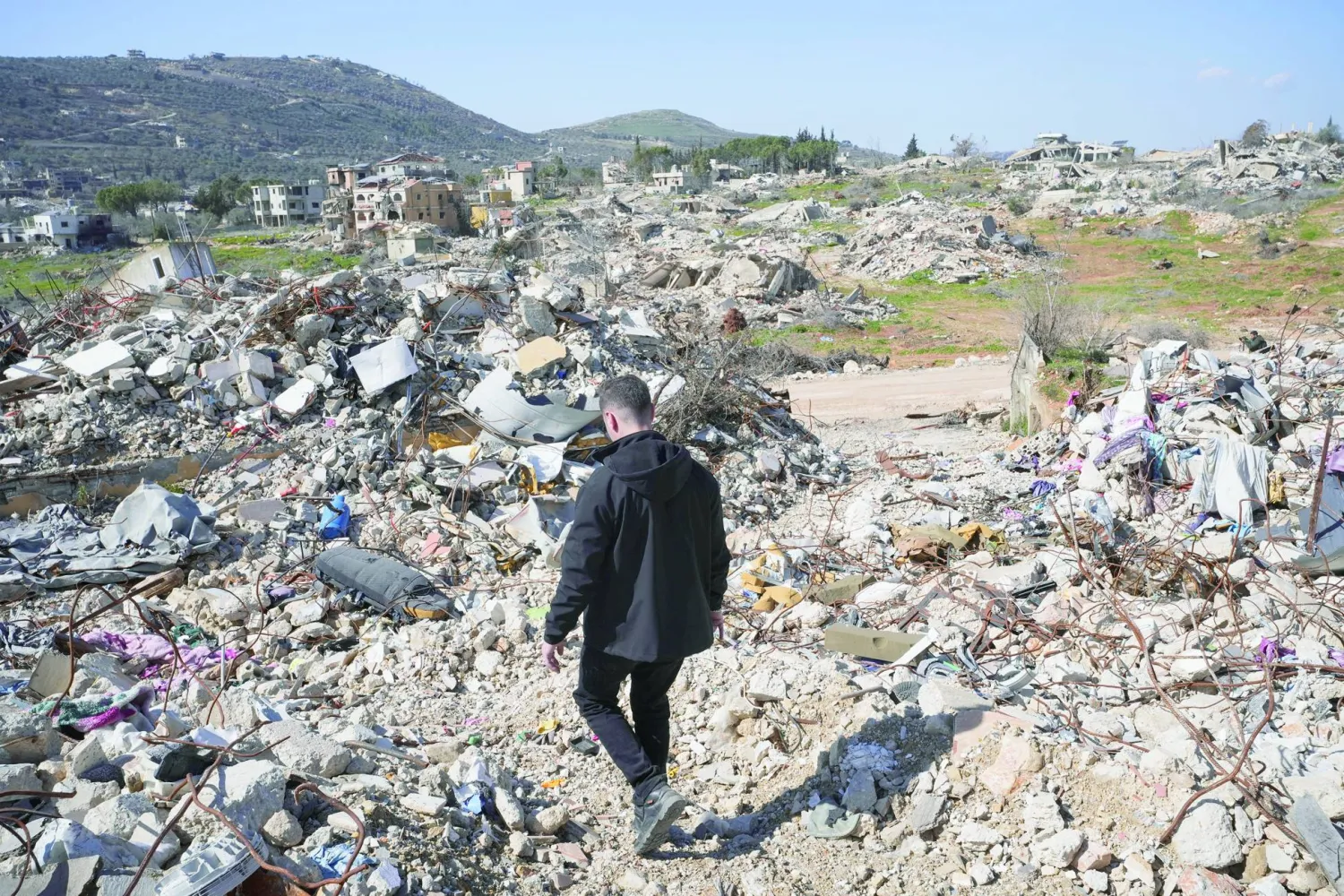 رجل يسير بين ركام المنازل في كفركلا (رويترز)
