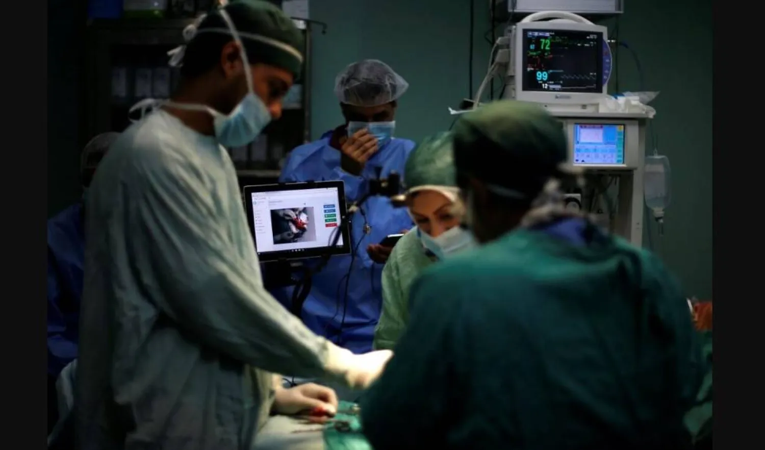 أطباء يتعاونون خلال إجراء عملية جراحية (رويترز)