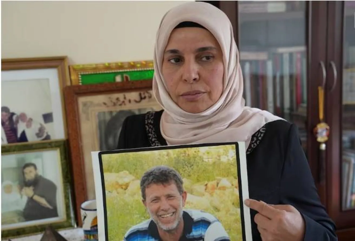 إيمان زوجة عميد الأسرى تحمل صورته (رويترز)