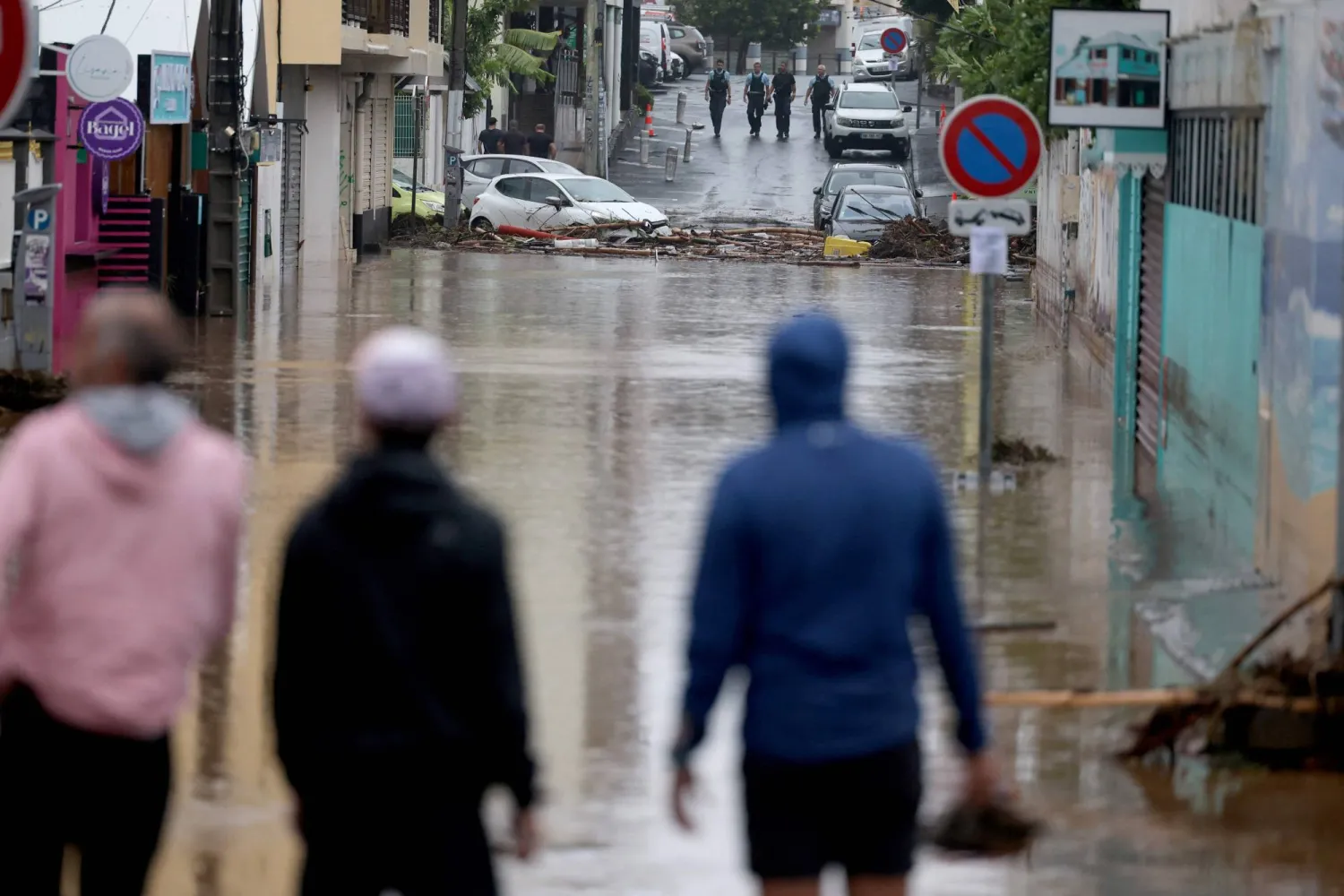 28 February 2025, France, Saint-Paul: Pedestrians and French gendarmerie officers stand next to a flooded road after cyclone "Garance" hit the French overseas island of La Reunion in the Indian Ocean. Photo: Richard Bouhet/AFP/dpa