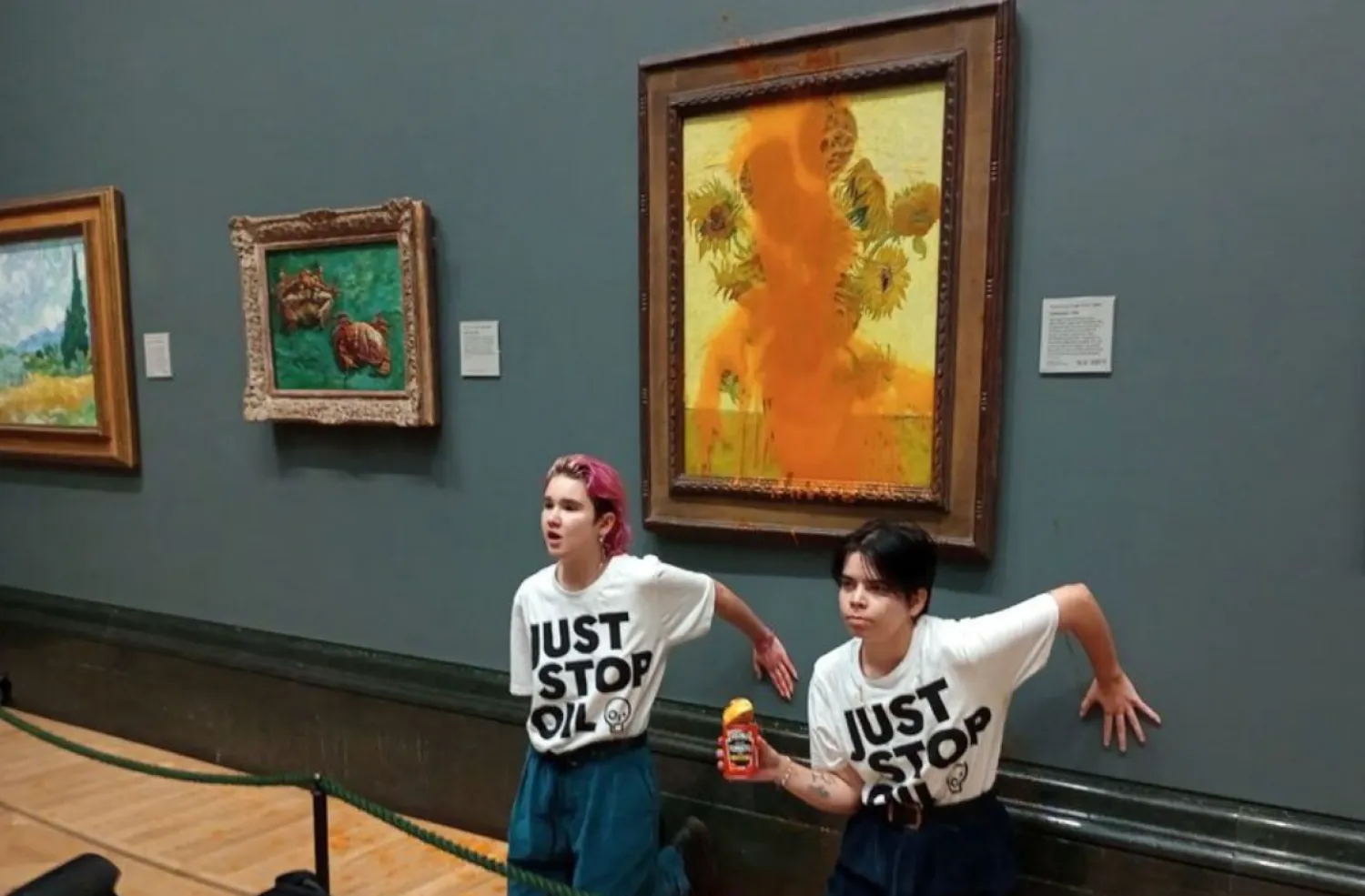 Activists of "Just Stop Oil" glue their hands to the wall after throwing soup at a van Gogh's painting "Sunflowers" at the National Gallery in London, Britain October 14, 2022. Just Stop Oil/Handout via REUTERS/File Photo 