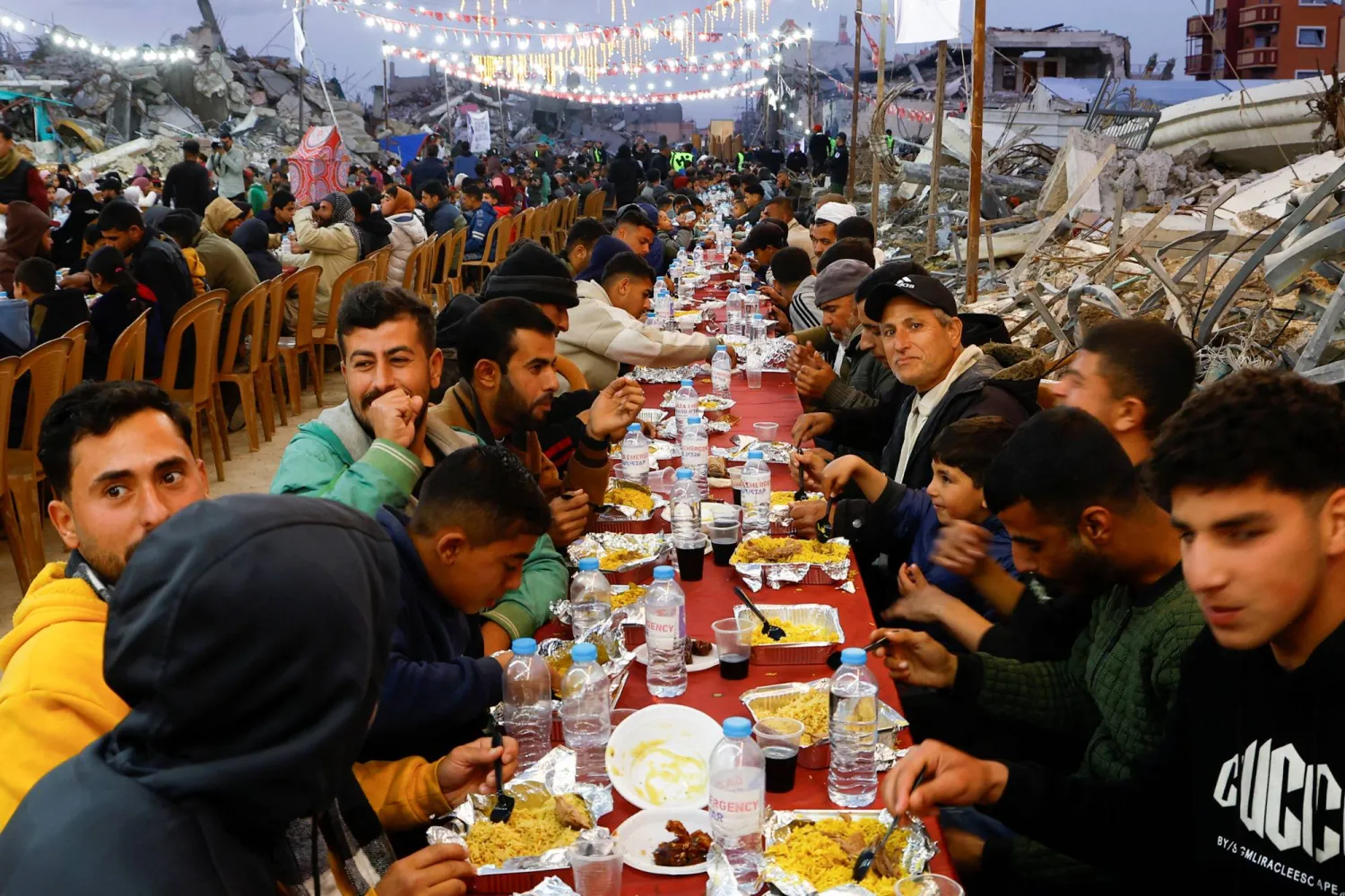 فلسطينيون يتناولون إفطار رمضان وسط أنقاض المباني التي دمرتها الحرب في رفح بجنوب قطاع غزة (رويترز)