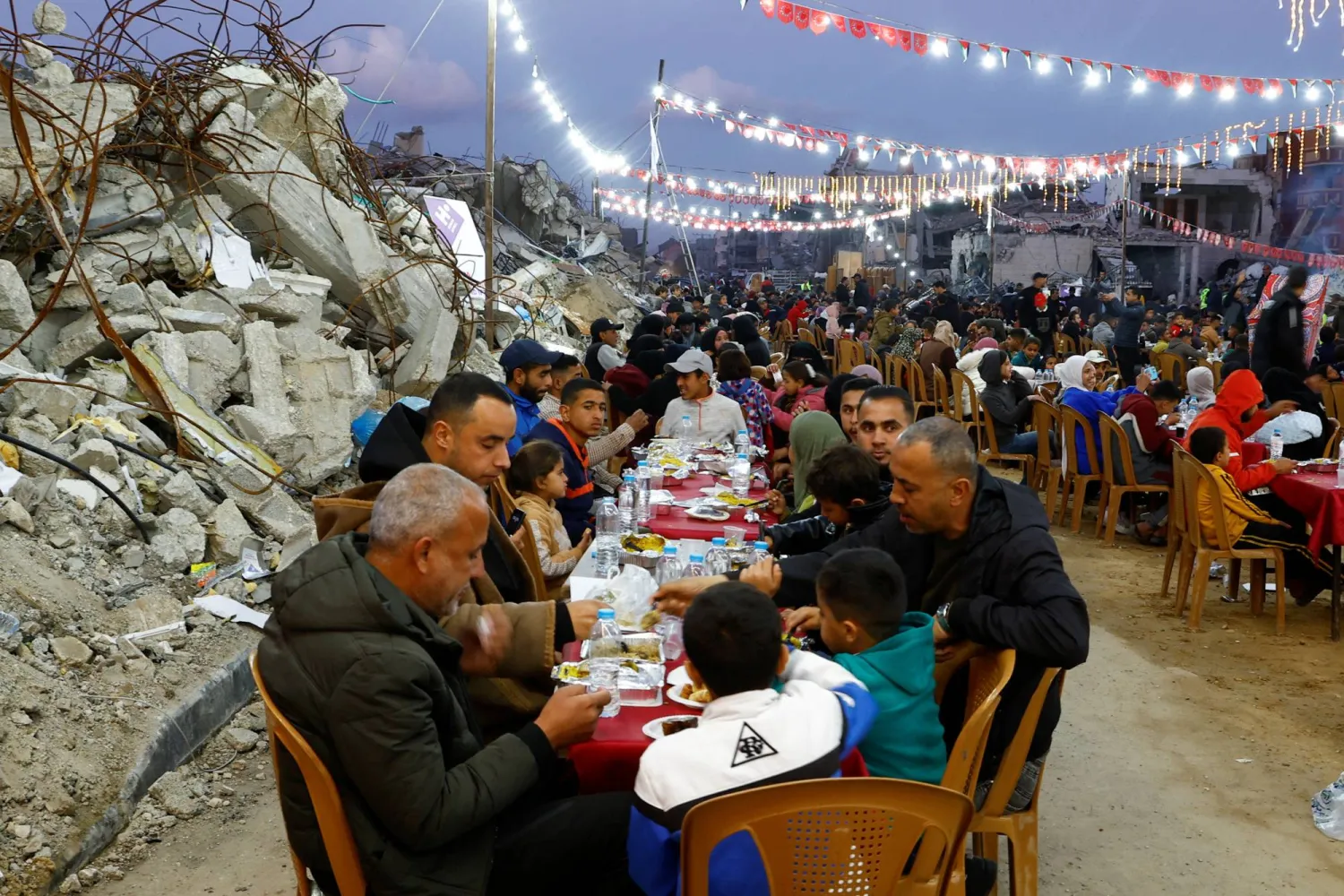 فلسطينيون يتناولون إفطار رمضان وسط أنقاض المباني التي دمرتها الحرب في رفح بجنوب قطاع غزة (رويترز)