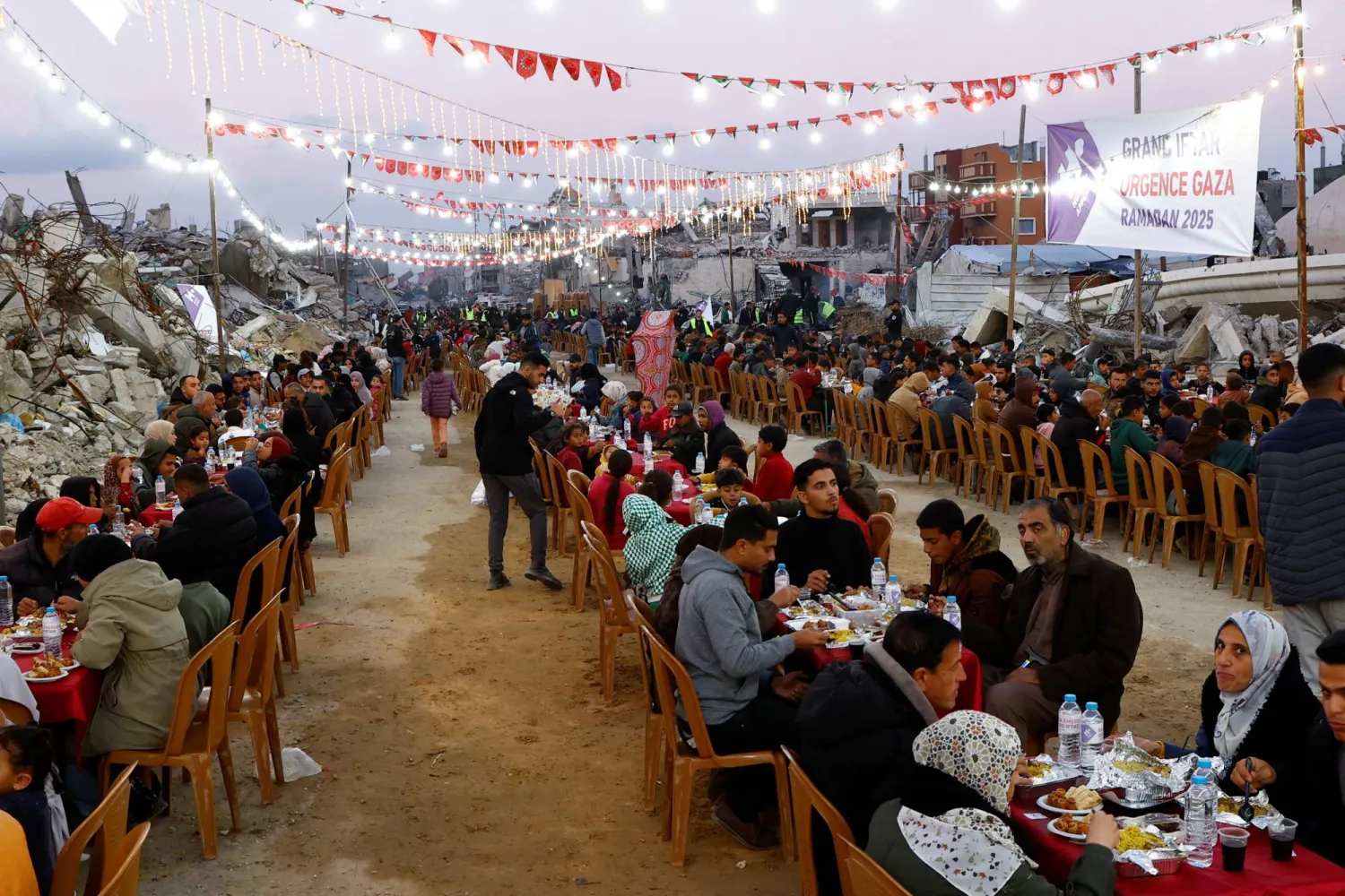 فلسطينيون يتناولون إفطار رمضان وسط أنقاض المباني التي دمرتها الحرب في رفح بجنوب قطاع غزة (رويترز)