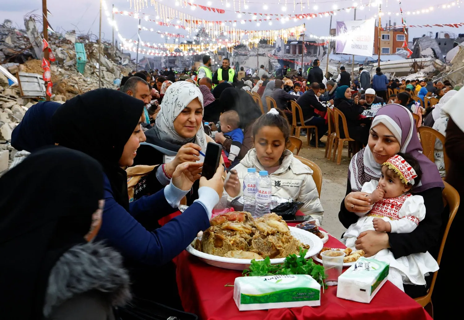 فلسطينيون يتناولون إفطار رمضان وسط أنقاض المباني التي دمرتها الحرب في رفح بجنوب قطاع غزة (رويترز)