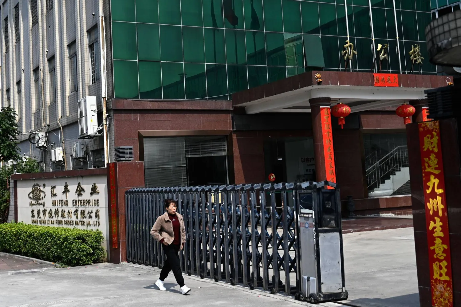 امرأة تسير نحو مدخل مصنع أحذية في منطقة صناعية بدونغقوان مقاطعة قوانغدونغ الجنوبية في الصين (أ.ف.ب)