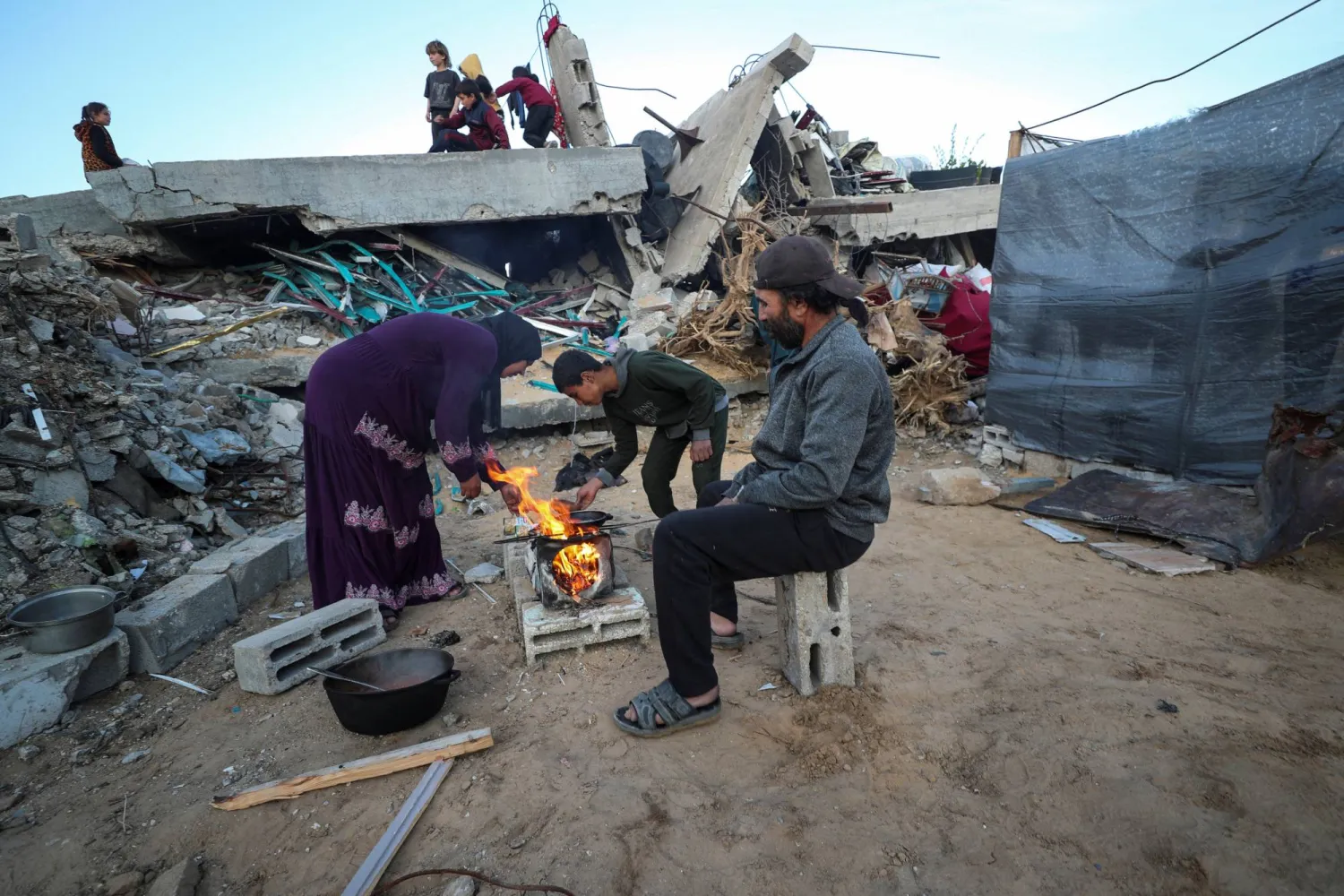 عائلة فلسطينية تشعل حطباً لإعداد وجبة الإفطار خلال ثاني أيام شهر رمضان في مخيم جباليا بقطاع غزة (رويترز)