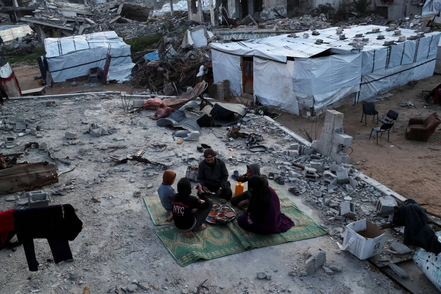 عائلة فلسطينية تتناول وجبة الإفطار في ثاني أيام شهر رمضان فوق حطام منزل بمخيم جباليا بقطاع غزة (رويترز)