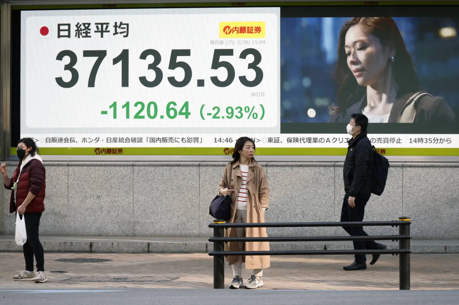 يمر المشاة أمام لوحة مؤشر سوق الأوراق المالية في طوكيو (وكالة حماية البيئة)