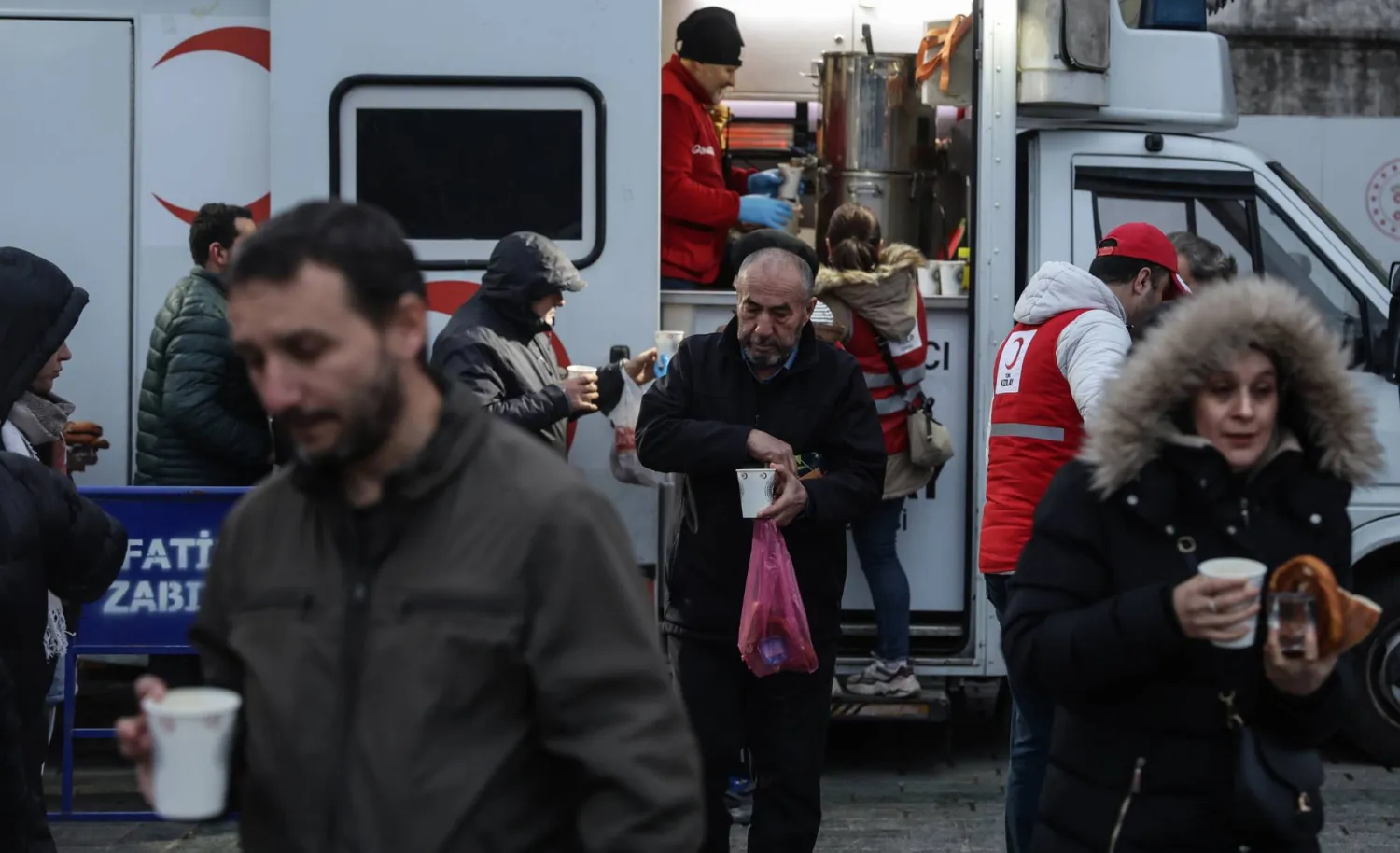أتراك يحصلون على الحساء الساخن ووجبات إفطار من سيارة للهلال الأحمر في ميدان السلطان أحمد في إسطنبول (إ.ب.أ)