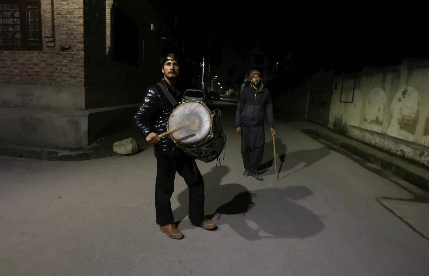 مسحراتي يسير في الشارع وهو يقرع الطبل ويدعو للاستيقاظ (إ.ب.أ)