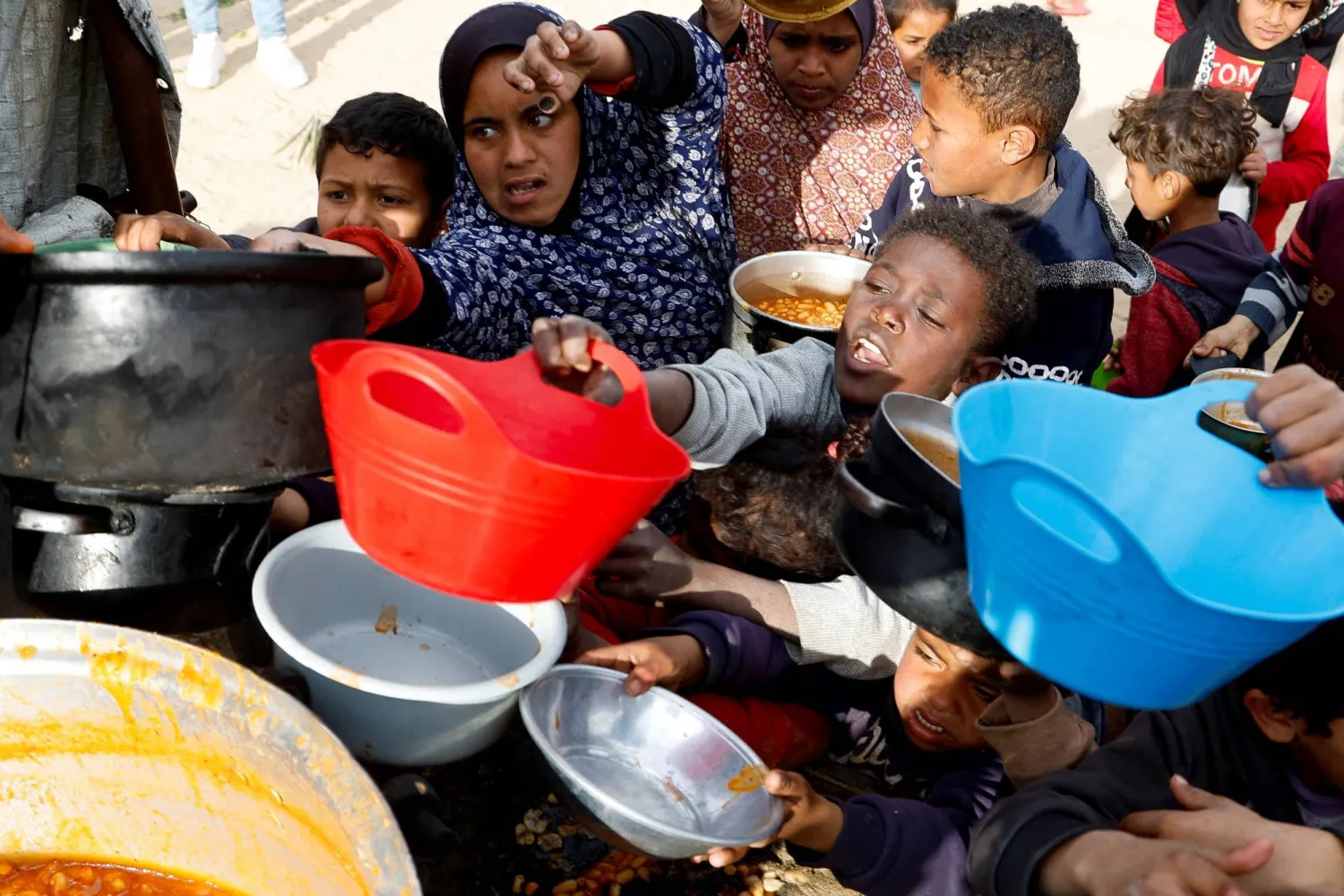 أطفال فلسطينيون يتجمعون لتلقي طعام أعده مطبخ خيري في خان يونس بجنوب قطاع غزة (رويترز)