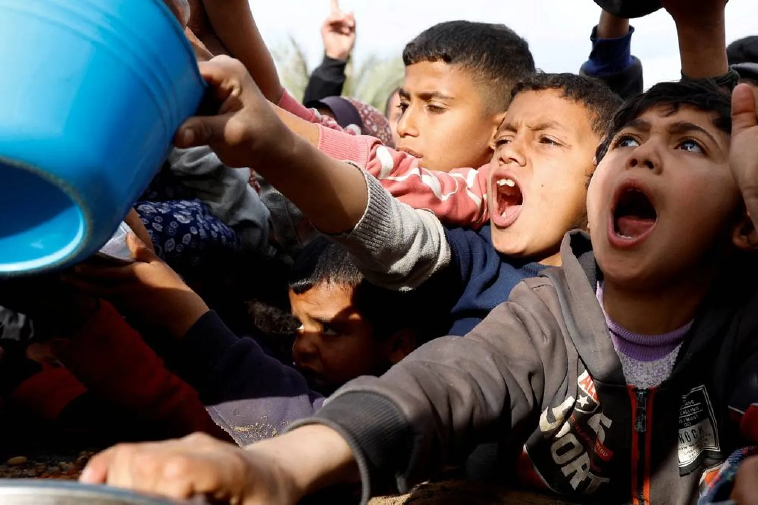  Palestinian children gather to receive food cooked by a charity kitchen, during the Muslim holy month of Ramadan, in Khan Younis, in the southern Gaza Strip, March 3, 2025. (Reuters)