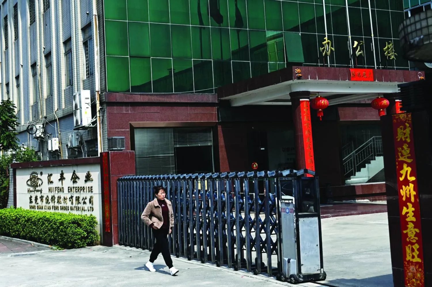 This photo taken on February 19, 2025 shows a woman walking towards the entrance of a shoe factory of Huifeng Enterprise at an industrial zone in Dongguan, China's southern Guangdong province. (Photo by Pedro PARDO / AFP)