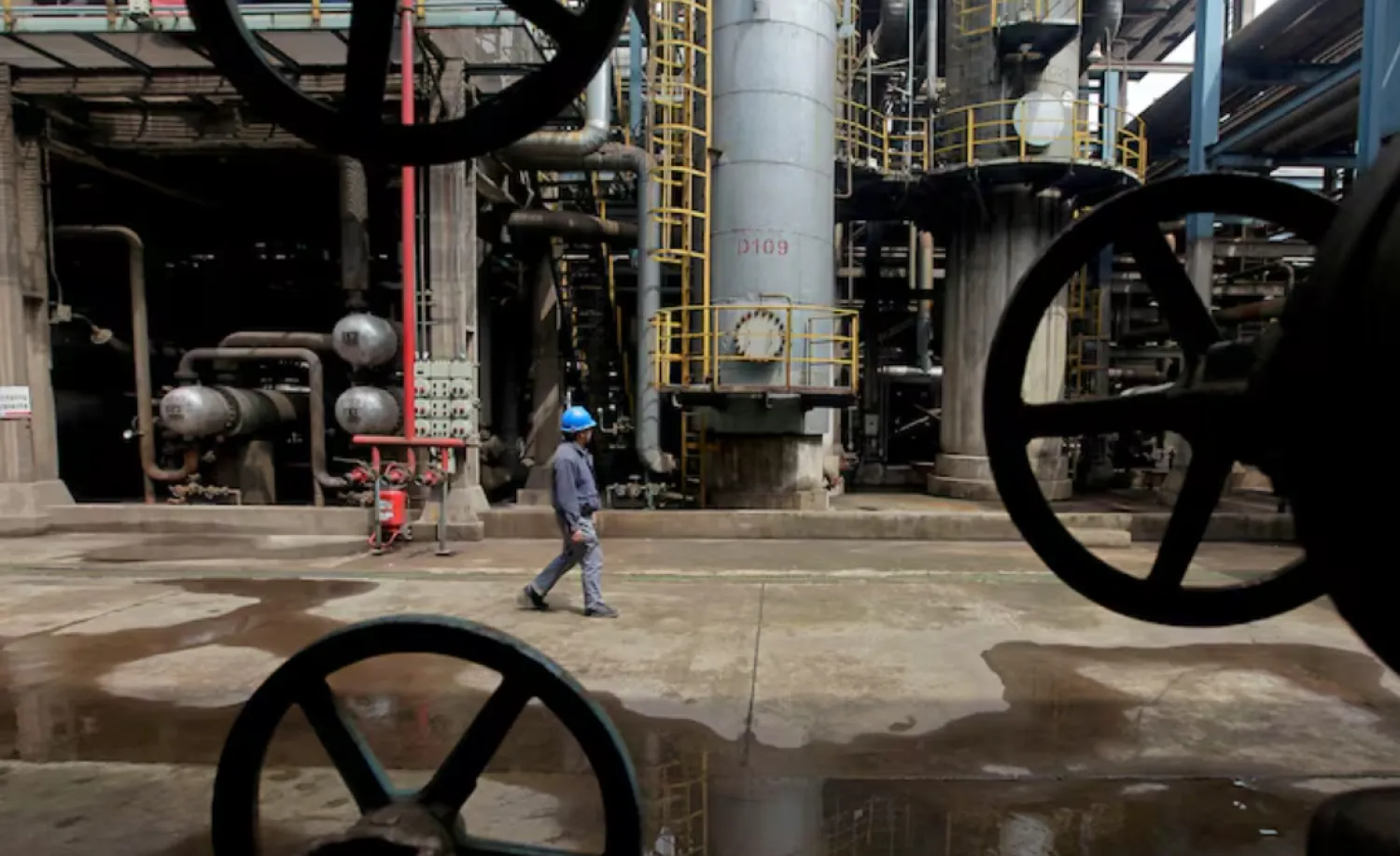 A worker walks past oil pipes at a refinery in Wuhan, Hubei province March 23, 2012. REUTERS/Stringer//File Photo